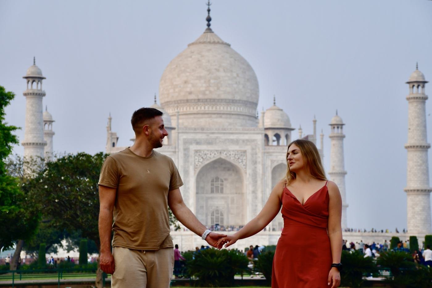 A couple holding hands in front of the Taj Mahal