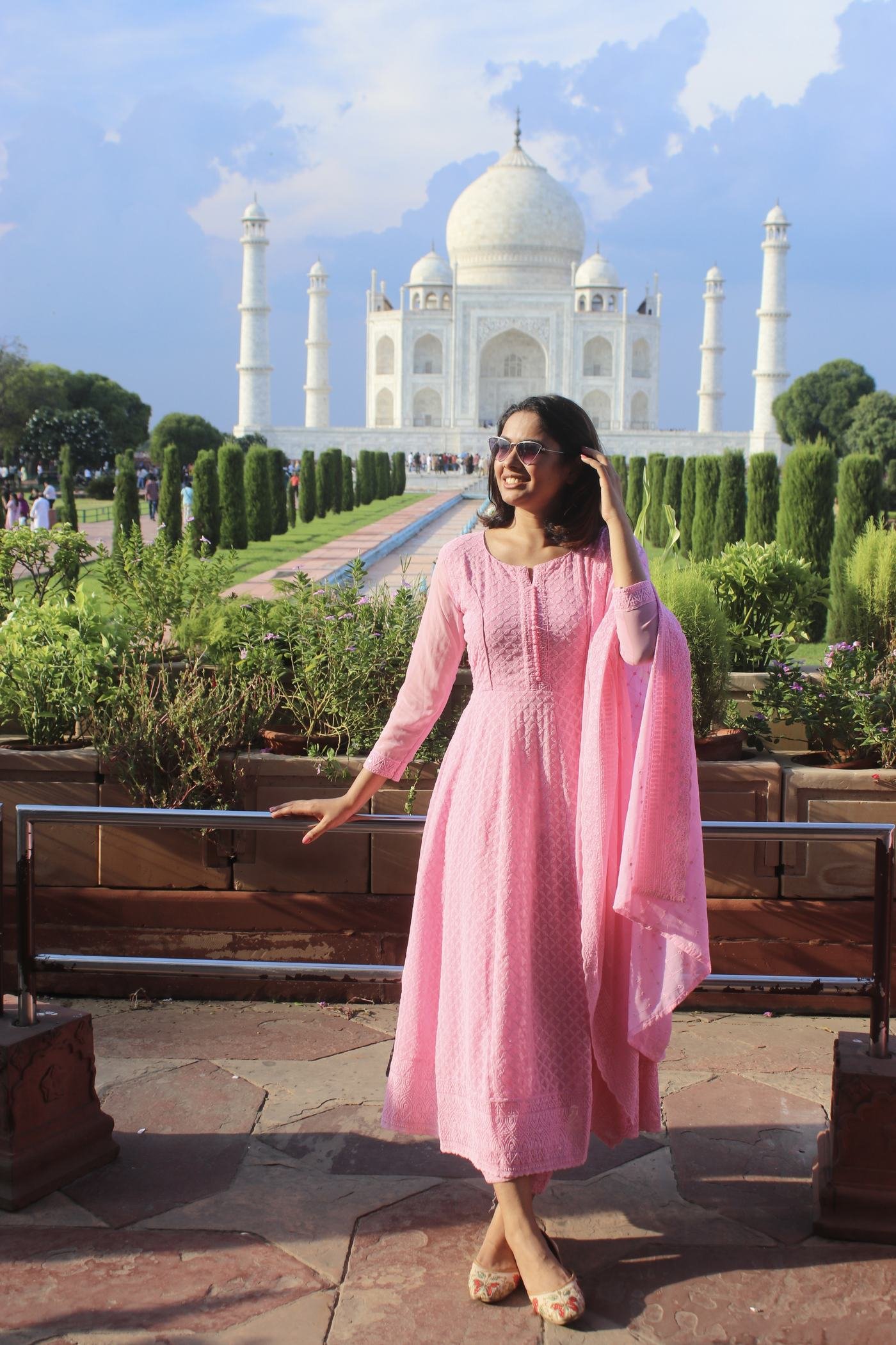 A traveller in a pink dress in front of the Taj Mahal in warm evening light