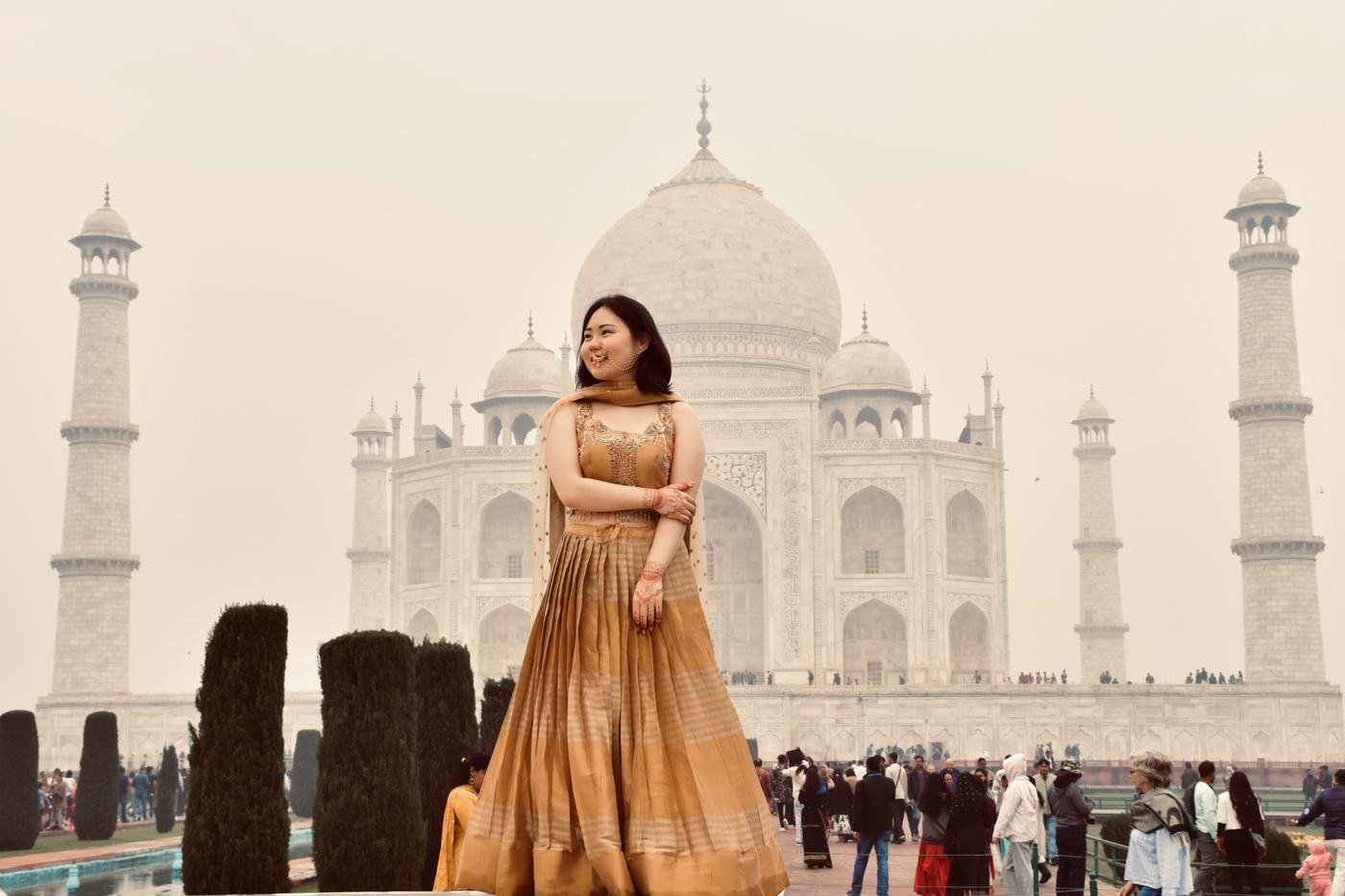 A traveller backlit by morning light in front of the Taj Mahal