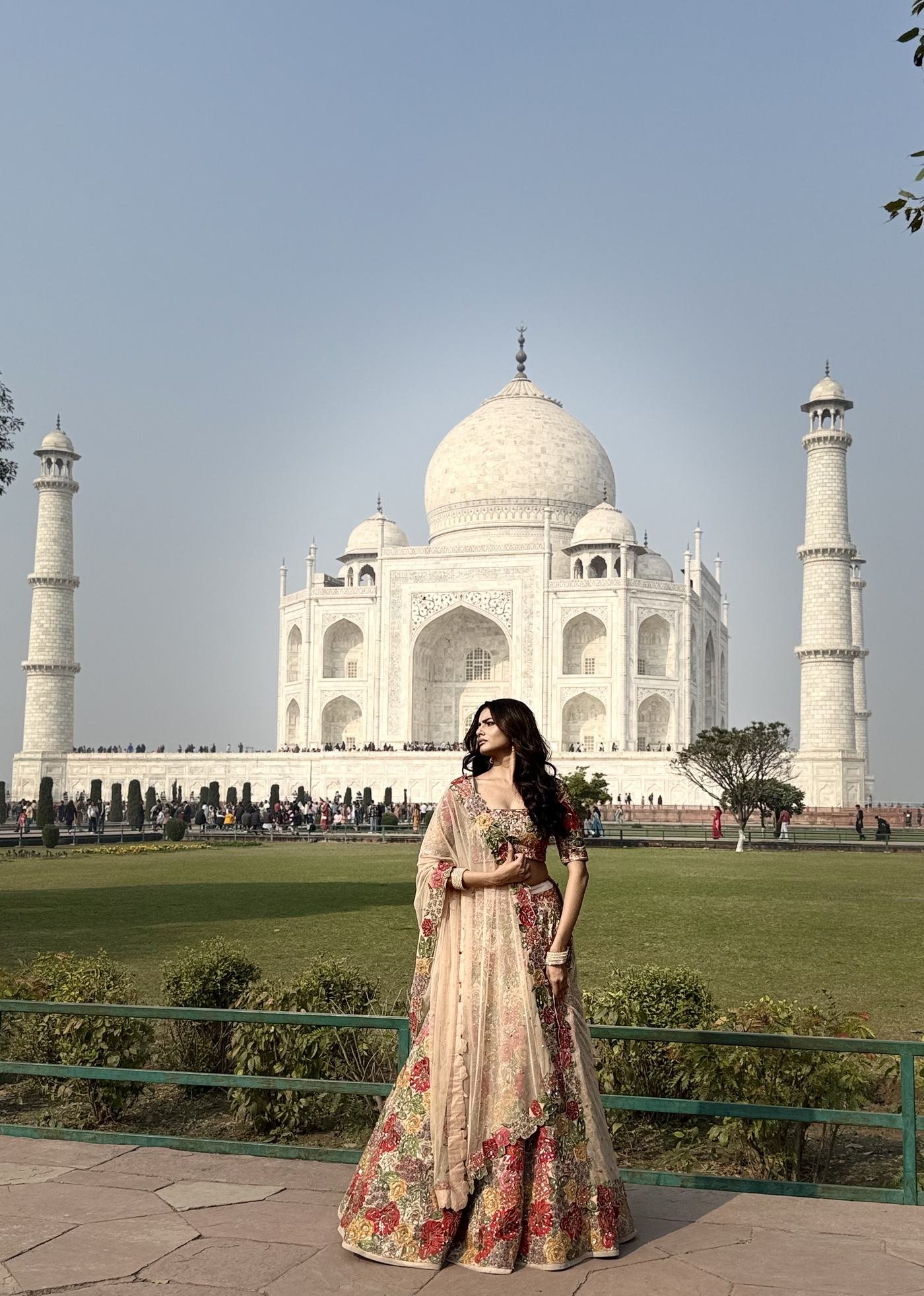 A traveller in an embroidered lehenga photographed in front of the Taj Mahal